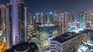 Dubai Marina havadan görünümden bir noktadan gece timelapse. Modern gökdelenler ve konut kuleleri parlayan windows ile aydınlatılmış. Yolda trafik