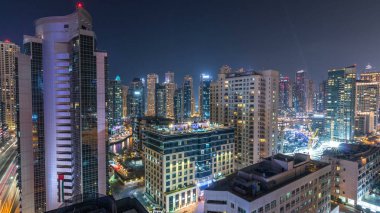 Dubai Marina havadan görünümden bir noktadan gece timelapse. Modern gökdelenler ve konut kuleleri parlayan windows ile aydınlatılmış. Yolda trafik