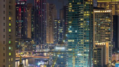 Dubai Marina havadan görünümden bir noktadan gece timelapse. Modern gökdelenler ve konut kuleleri parlayan windows ile aydınlatılmış. Köprüde trafik. Su yansımalar