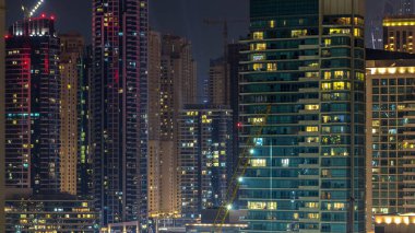 Dubai Marina havadan görünümden bir noktadan gece timelapse. Modern gökdelenler ve konut kuleleri parlayan windows ile aydınlatılmış. Yolda trafik