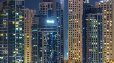 Çok öykülü modern cam ve metal binalar gece timelapse yanar içinde parlayan pencere eşiği. Geceleri aydınlatılan evler. Dubai Yat Limanı ve Jbr, Birleşik Arap Emirlikleri
