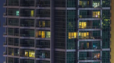 Çok öykülü modern cam ve metal kadar ışık gece timelapse bina konut içinde parlayan pencere eşiği. Daireler insanlar. Geceleri aydınlatılan evler. Dubai Yat Limanı ve Jbr, Birleşik Arap Emirlikleri. Vınlamak dışarı