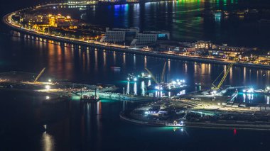 Palm Jumeirah Adası gece timelapse hava görünümünü. Villa, otel ve yat ile üstten görünüm. Yeni cruise terminal inşaat süreci