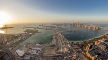 Palm Jumeirah Adası gün gece geçiş timelapse için hava gün batımı manzarası. Üstten görünüm ışıklı Villaları, otelleri ve yatlar ile akşam. Yeni cruise terminal inşaat süreci