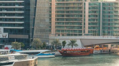 Yat ve tekne shoping mall kalıyor ve Dubai Marina bölge timelapse bir köprü altında geçen turist. Akşam gün batımı sırasında hava üstten görünüm.