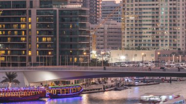 Yat ve tekne shoping alışveriş merkezi kalmak ve bir köprünün altından geçen Dubai Yat Limanı ilçe gün içinde gece geçiş timelapse için turist. Akşam güneş battıktan sonra hava üstten görünüm.