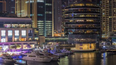 Shoping Alışveriş Merkezi, restoranlar, kuleleri ve yatlar gece timelapse, Birleşik Arap Emirlikleri hava vew Dubai Marina. Kanal ile aydınlatılmış binalar ve waterfront üstten görünüm