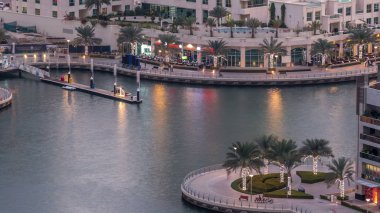 Geçen tekneler ve avuç içi gün gece ile promenade ile lüks Dubai Yat Limanı kanal timelapse geçiş, yukarıdan bakışta akşam güneş battıktan sonra Top. Dubai, Birleşik Arap Emirlikleri