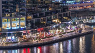 Lüks Dubai Yat Limanı kanal geçen tekneler ile ve mesire Restoran gece timelapse ile üst görüntülemek üzerinden yukarıda ile ışıklandırılmış gökdelenler. Dubai, Birleşik Arap Emirlikleri