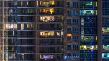 Çok öykülü modern cam konut içinde parlayan pencere eşiği ışık gece timelapse bina. Daireler insanlar. Evler de akşam aydınlatılmış. Dubai Marina, Birleşik Arap Emirlikleri.