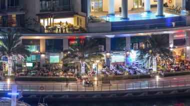 Lüks Dubai Yat Limanı kanal geçen tekneler ile ve mesire Restoran gece timelapse ile üst görüntülemek üzerinden yukarıda ile ışıklandırılmış gökdelenler. Dubai, Birleşik Arap Emirlikleri