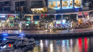 Lüks Dubai Yat Limanı kanal geçen tekneler ile ve mesire Restoran gece timelapse ile üst görüntülemek üzerinden yukarıda ile ışıklandırılmış gökdelenler. Dubai, Birleşik Arap Emirlikleri