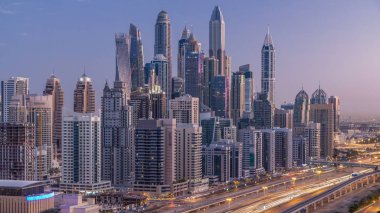 Dubai Yat Limanı gökdelenler hava üstten görünüm güneş doğmadan önce Jlt gelen Dubai gece gün timelapse, Birleşik Arap Emirlikleri için. Işıklı modern kuleleri ve Şeyh zayed yolu üzerinde trafik.