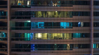 Çok öykülü modern cam konut içinde parlayan pencere eşiği ışık gece timelapse bina. Daireler insanlar. Akşam aydınlatılmış gökdelenler. Dubai Marina, Birleşik Arap Emirlikleri.