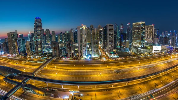 Dubai marina with traffic on sheikh zayed road panorama day to night transition timelapse lights turn on. The night illumination of skyscrapers, UAE. Aerial view from JLT