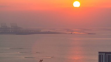 Bluewaters Island Hava timelapse üzerinde gün batımı. Palm Jebel Ali bir arka plan üzerinde. Bir su yansıyan güneş