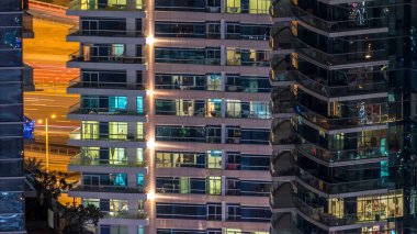 Çok öykülü modern cam ve metal kadar ışık gece timelapse bina konut içinde parlayan pencere eşiği. Daireler insanlar. Geceleri aydınlatılan evler. Dubai, Birleşik Arap Emirlikleri. Sağa çevir