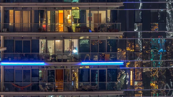 多层现代玻璃和金属住宅建筑的发光窗户在夜间亮起 公寓里的人房子在晚上灯火通明 Uae 向左平移 — 图库照片