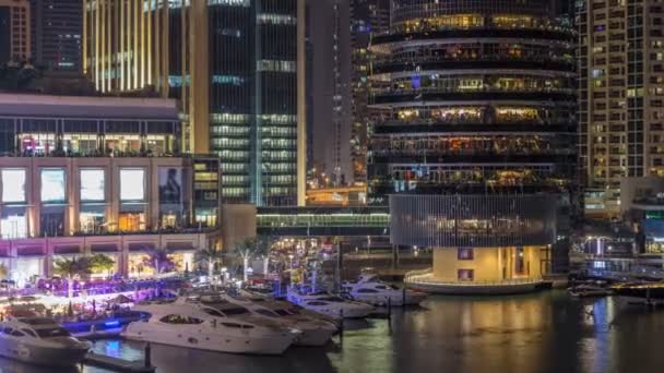 Veta aérea de Dubai Marina con centro comercial, restaurantes, torres y yates night timelapse, Emiratos Árabes Unidos . — Vídeos de Stock