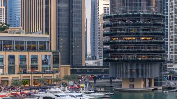 Vew aéreo de Dubai Marina com shopping center, restaurantes, torres e iates dia a noite timelapse, Emirados Árabes Unidos . — Vídeo de Stock