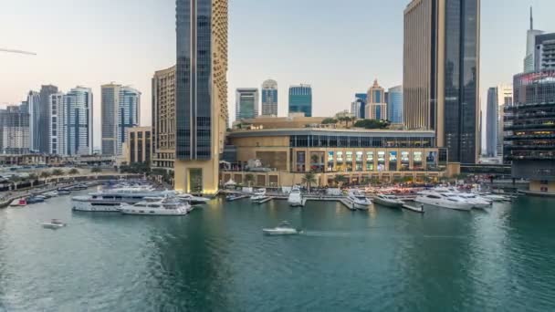 Vew aéreo de Dubai Marina com shopping center, restaurantes, torres e iates dia a noite timelapse, Emirados Árabes Unidos . — Vídeo de Stock