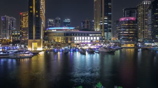 Veta aérea de Dubai Marina con centro comercial, restaurantes, torres y yates night timelapse, Emiratos Árabes Unidos . — Vídeos de Stock