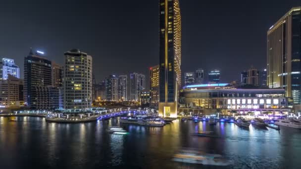 Veta aérea de Dubai Marina con centro comercial, restaurantes, torres y yates night timelapse, Emiratos Árabes Unidos . — Vídeo de stock
