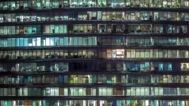 Noche de trabajo en edificio de oficinas de vidrio con numerosas oficinas con paredes de vidrio y ventanas timelapse — Vídeo de stock