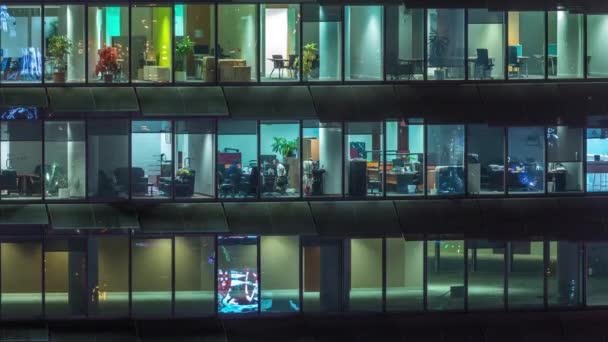 Noche de trabajo en edificio de oficinas de vidrio con numerosas oficinas con paredes de vidrio y ventanas timelapse — Vídeo de stock