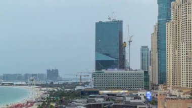 Dubai, Bae'de gece saatlerinden geceye gökdelenlerle Jbr'de yürüyen plaj ve turistlerin havadan görünümü