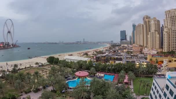 Vista aérea da praia e turistas caminhando no JBR com arranha-céus dia a noite timelapse em Dubai, Emirados Árabes Unidos — Vídeo de Stock