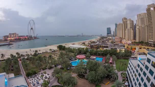 Vue aérienne de la plage et des touristes marchant dans JBR avec des gratte-ciel de jour comme de nuit à Dubaï, Émirats Arabes Unis — Video