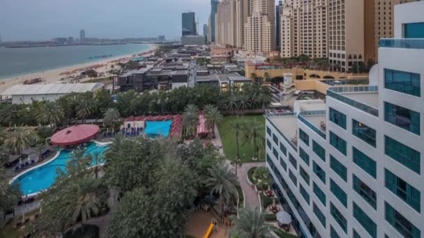 Vista aérea da praia e turistas caminhando no JBR com arranha-céus dia a noite timelapse em Dubai, Emirados Árabes Unidos — Vídeo de Stock