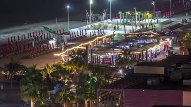 Vista aérea de la playa y los turistas caminando en JBR con rascacielos noche timelapse en Dubai, Emiratos Árabes Unidos — Vídeo de stock