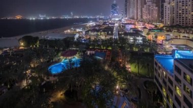Dubai, Bae'de gökdelenler gece saatlerinde Jbr'de yürüyen plaj ve turistlerin havadan görünümü