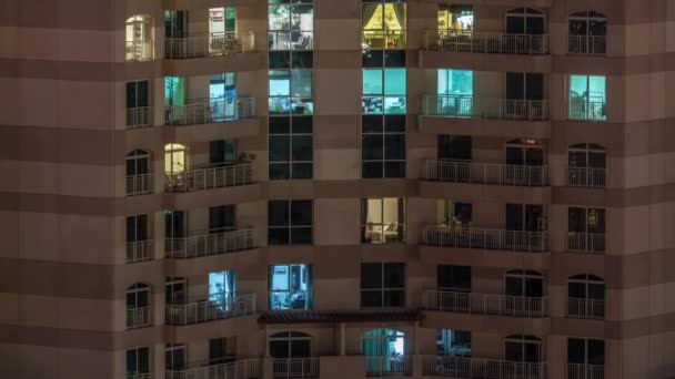 Ventanas del edificio de varios pisos con iluminación interior y personas en movimiento en apartamentos timelapse . — Vídeo de stock