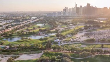 Golf sahası ve Jumeirah göl kuleleri gökdelenler gün batımı timelapse önce,, Dubai, Birleşik Arap Emirlikleri