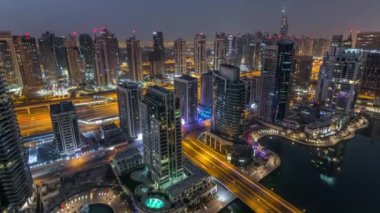 Dubai Marina gece gündüz timelapse havadan üst görünümü. Modern kuleler ve yolda trafik