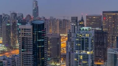 Dubai Marina gece gündüz timelapse havadan üst görünümü. Modern kuleler ve yolda trafik