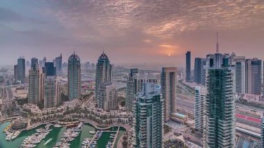 Dubai Marina timelapse gündoğumu havadan üst görünümü. Modern kuleler ve yolda trafik