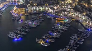Dubai marina gece zaman atlamalı yüzen yatlar havadan görünümü. Beyaz tekneler kanal suyunda.