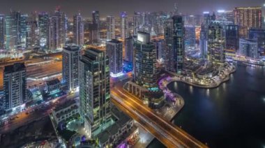 Dubai Marina gece timelapse havadan üst görünümü. Modern kuleler ve yolda trafik