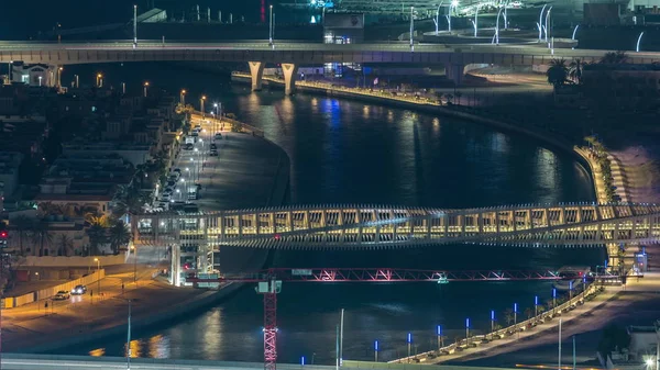 Dubai water canal with footbridge aerial night timelapse from Downtown skyscrapers rooftop