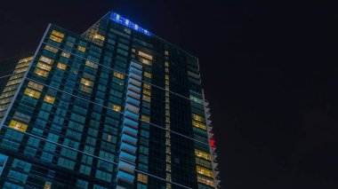 Parlayan pencereler mimarisi timelapse ile modern gökdelen üzerinde bulutlar ile Night Sky.