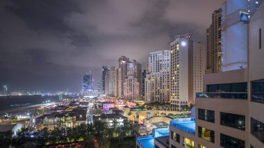 Dubai, Bae'de gökdelenler gece saatlerinde Jbr'de yürüyen plaj ve turistlerin havadan görünümü
