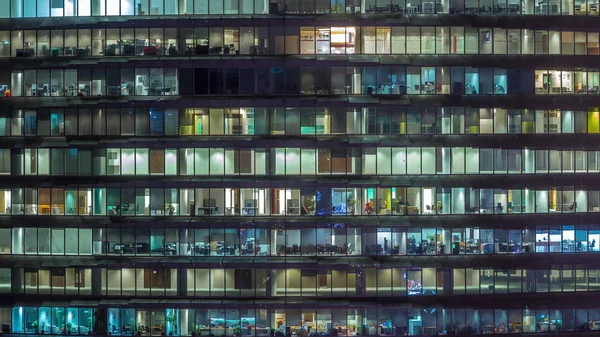 Soirée de travail dans un immeuble de bureaux en verre avec de nombreux bureaux avec des murs en verre et des fenêtres timelapse — Photo