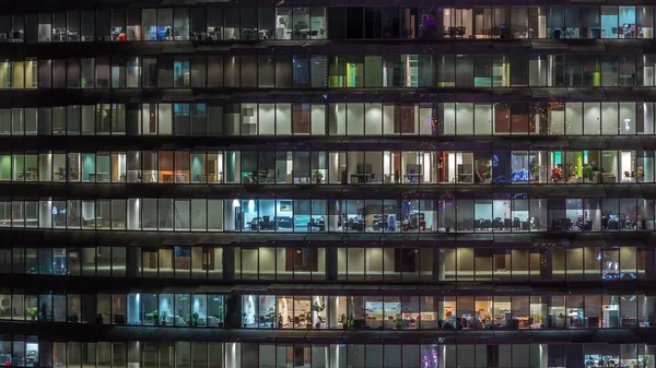 Wieczór roboczy w szklanym budynku biurowym z licznymi biurami ze szklanymi ścianami i oknami timelapse — Zdjęcie stockowe