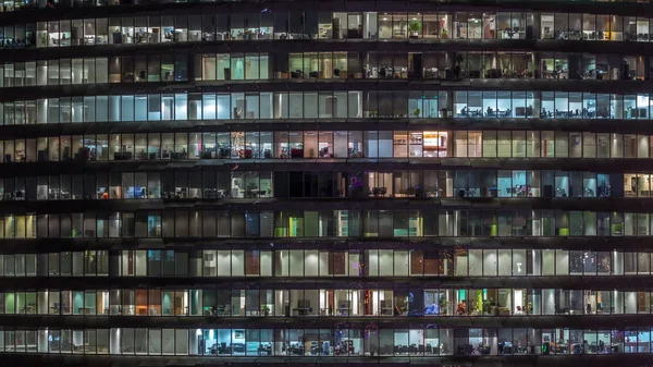 Noche de trabajo en edificio de oficinas de vidrio con numerosas oficinas con paredes de vidrio y ventanas timelapse —  Fotos de Stock