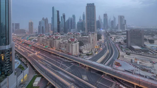 Dubai skyline céntrico noche a día timelapse aéreo con el tráfico en la carretera — Foto de Stock