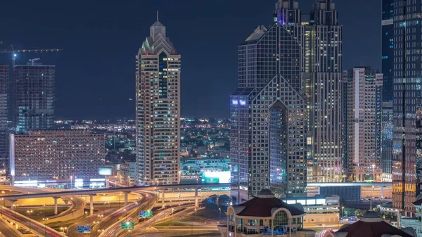 두바이 타임랩스의 조명이 켜진 고층 빌딩과 도로 교차로의 공중 전경 — 스톡 사진